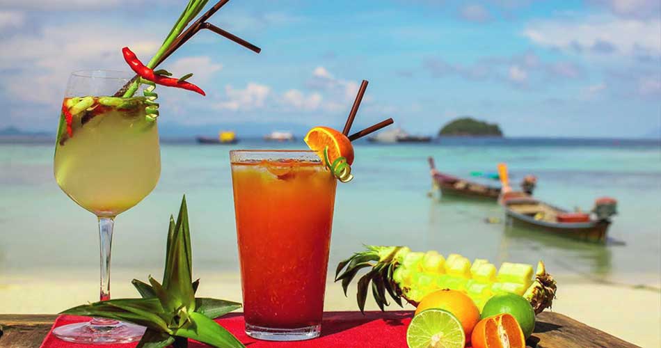 Koh Lipe restaurant and bar: picture of cocktails with slightly out of focus view of sunrise beach on Koh Lipe in the backgroundKoh Lipe restaurant and bar: picture of cocktails with slightly out of focus view of sunrise beach on Koh Lipe in the background